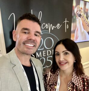 Newcastle Cosmetic Doctor and Sharon smiling, background cosmedicon conference poster