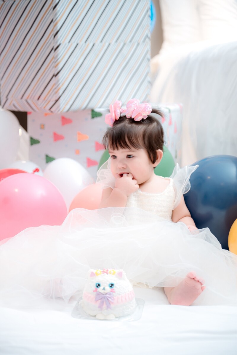 Trudy playing near balloons in birthday outfit with stuffed animal