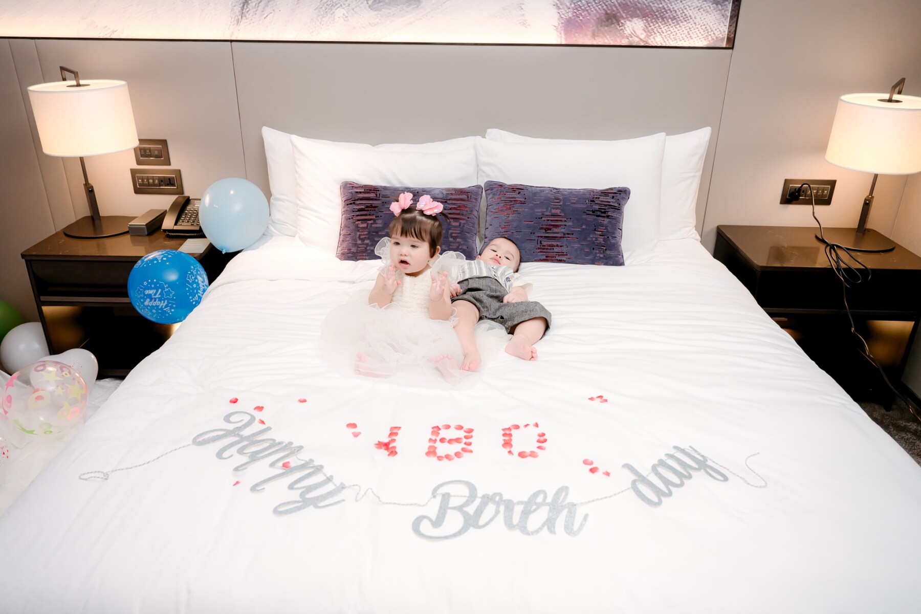 Twins lying on bed with Happy Birthday decoration