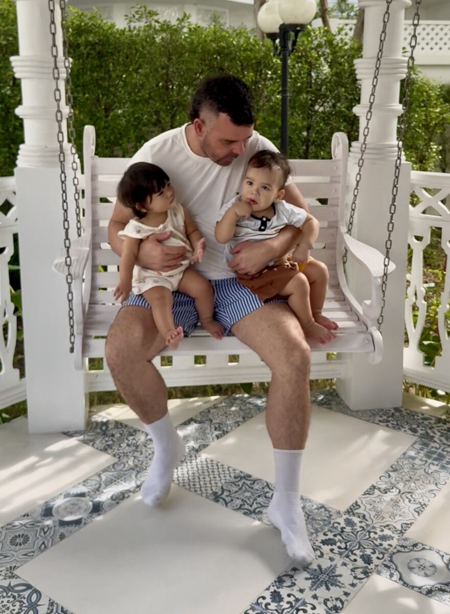 Father sitting with twins on swing