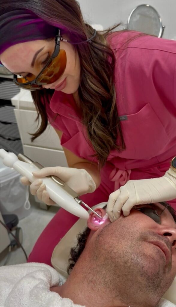 Sharon Leayr performing laser treatment on side of male face