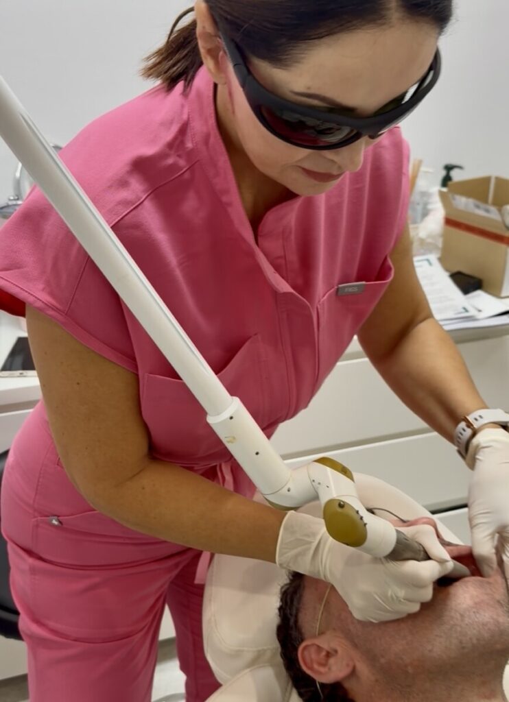 Sharon Leayr performing laser treatment on male patient's face